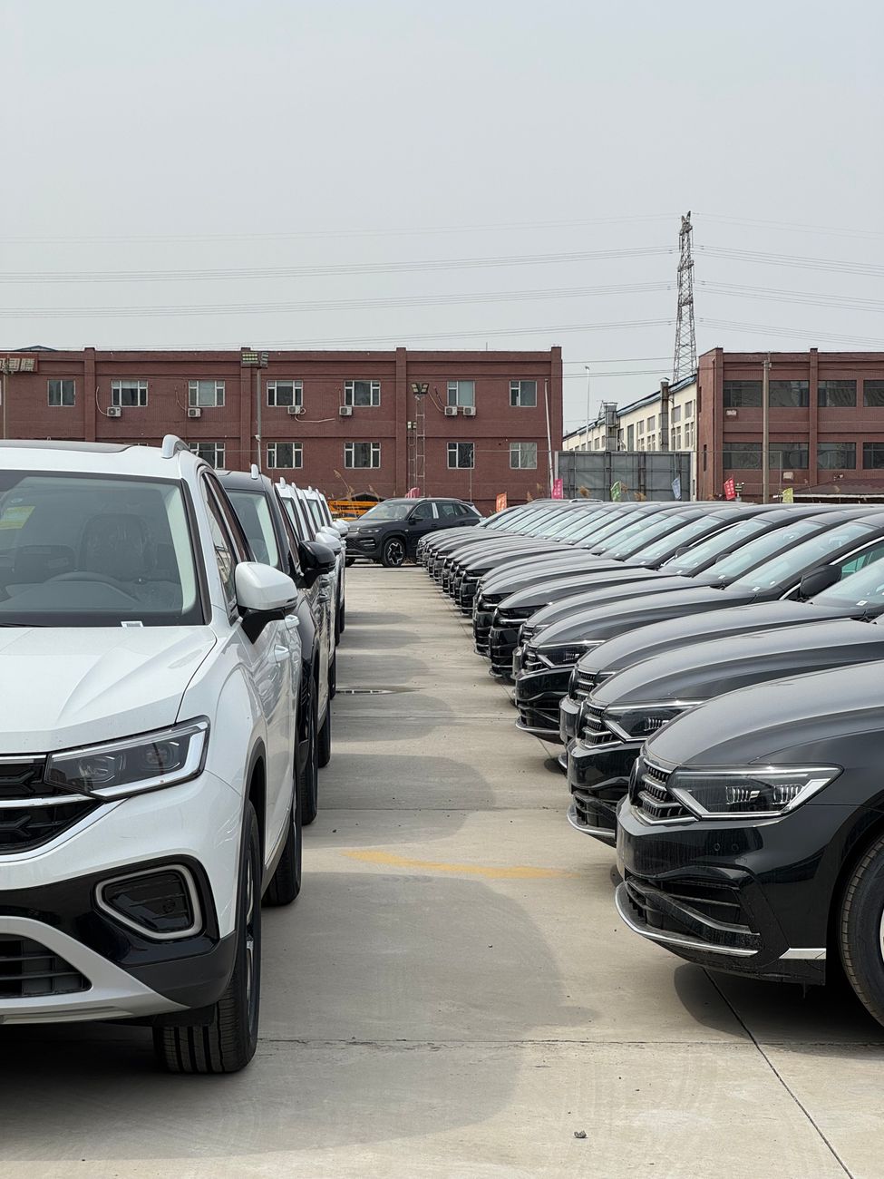 row of new cars in industrial parking lot